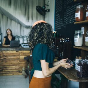 A woman selects organic produce in a sustainable grocery store, emphasizing eco-friendly shopping habits.