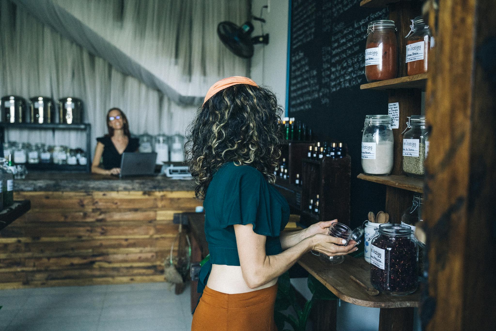 A woman selects organic produce in a sustainable grocery store, emphasizing eco-friendly shopping habits.